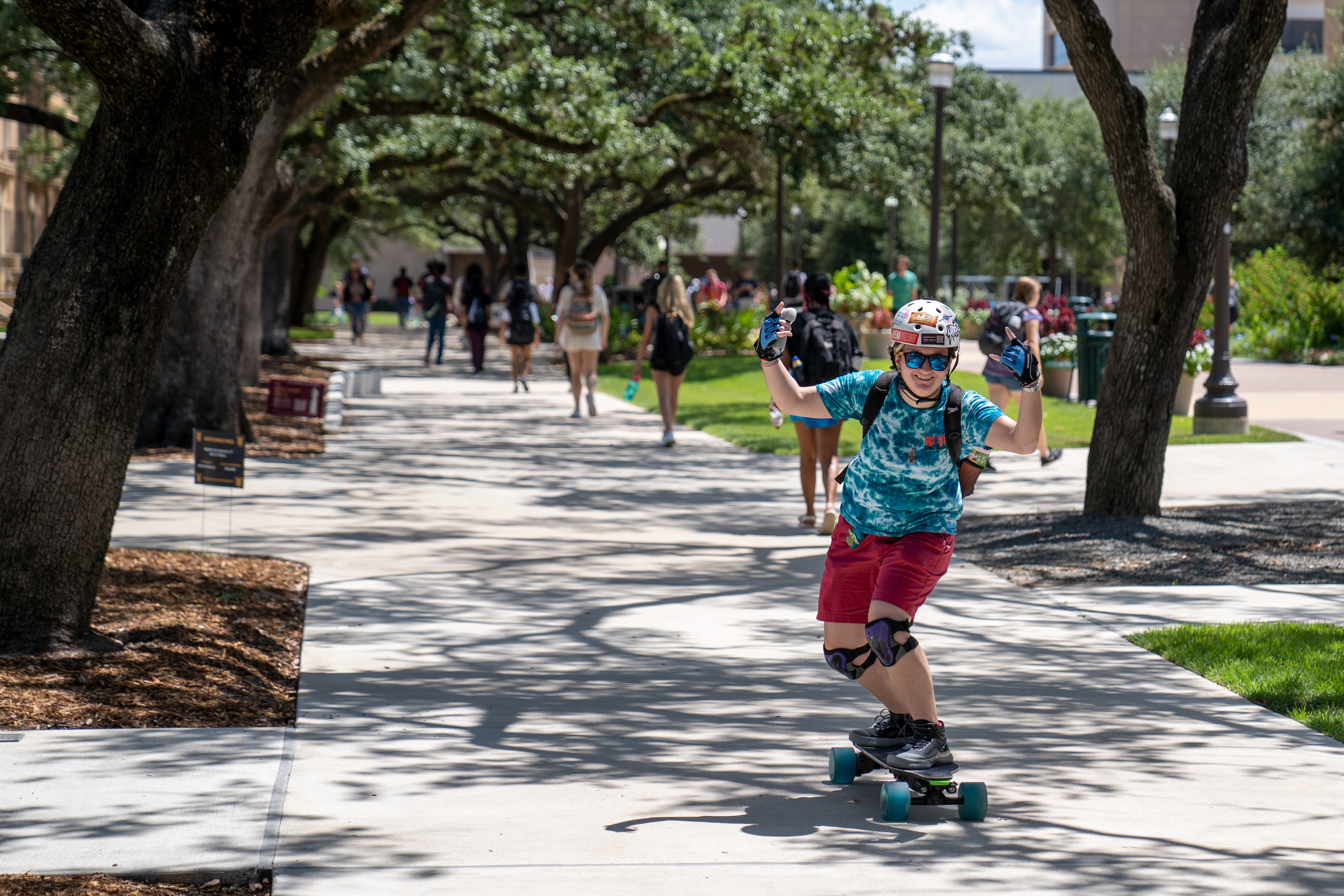 Student skateboarding on campus sidewalk